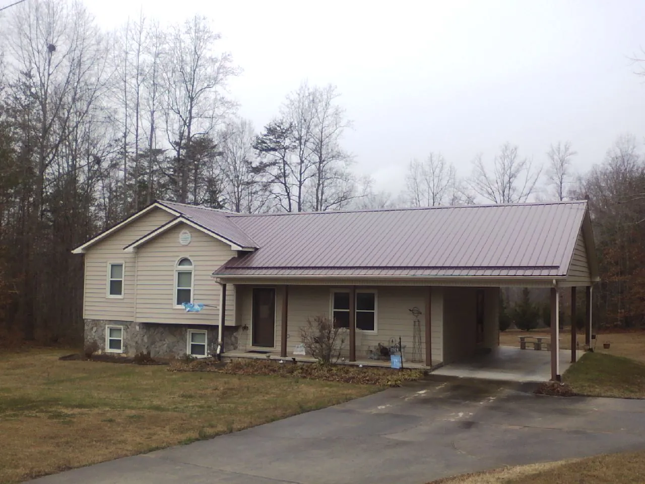 Burgundy metal roof on a tan split level home with an attached carport in Kirkland