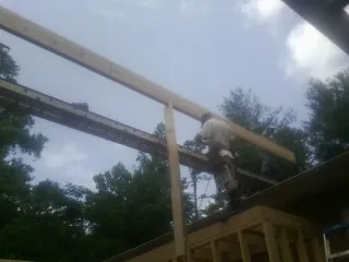 Carpenter setting a ridge beam over a new addition frame — Ice Dam Removal by Roofing Brothers in Kirkland