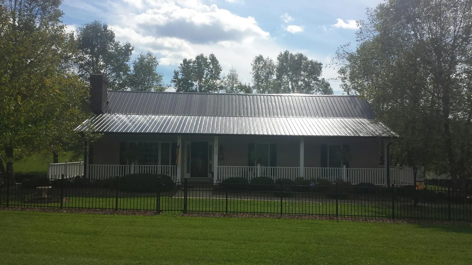 Gray metal roof on a brick ranch with a full width front porch — Gutter Guard Installation work by our crew in Kirkland